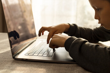 10-year-old boy carefully studies using a laptop, typing on a keyboard