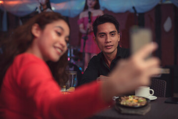 A woman takes a selfie with her cellphone as a remembrance of their first meeting and date.