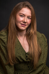 Portrait of a young red-haired woman in a dark studio