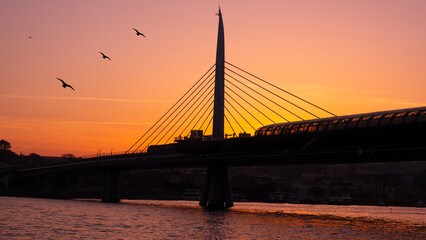 Obraz premium Beautiful sunset, Golden hours, Golden Horn metro bridge and the view of the Golden Horn in Istanbul, the sunset, the birds heading towards the sun, The image with space and text area.