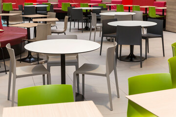 Multicolored empty tables at the food court in the mall. Entertainment and recreation. Close-up.