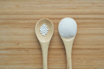 comparing Sugar Substitute sweetener and raw sugar on a wooden spoon 