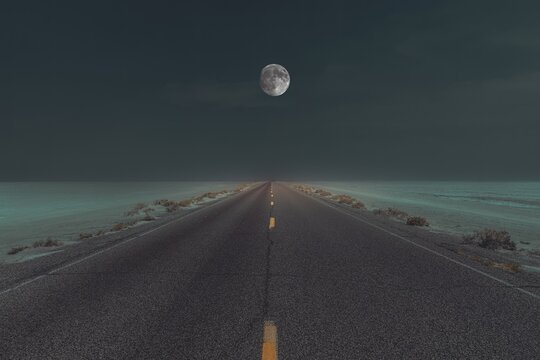 Straight road through the salt lfat at night with the full moon in the sky