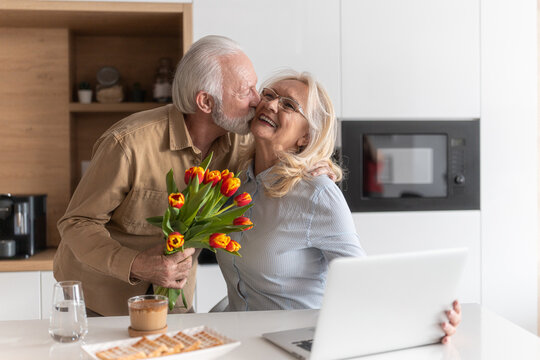 Senior couple in kitchen, man brought flowers to his wife - Powered by Adobe
