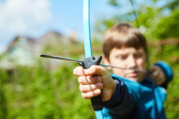 A sports bow in the hands of a boy's child. Sports shooting. - obrazy, fototapety, plakaty