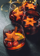 Table close-up still-life with Mulled wine with spices, fruits, and cinnamon served in thin glasses. Hot beverages during the cold season or Christmas and New Year celebration concept image - obrazy, fototapety, plakaty