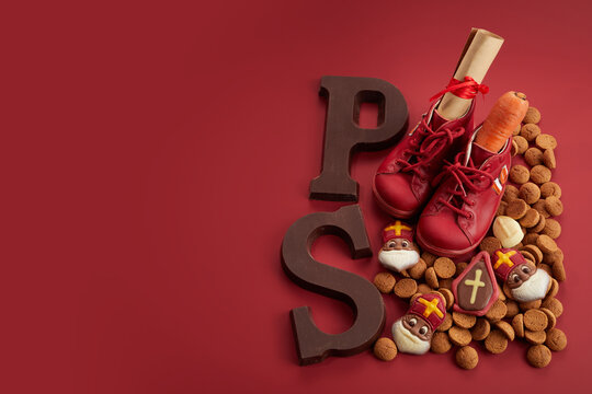 Saint Nicholas - Sinterklaas day with shoe, carrot and traditional sweets on red background