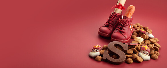 Saint Nicholas - Sinterklaas day with shoe, carrot and traditional sweets on red background