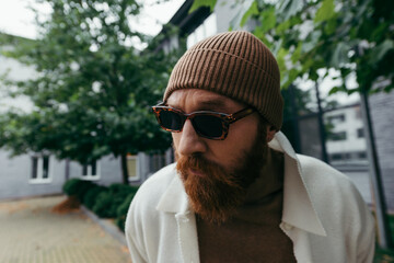 suspicious man with beard in stylish sunglasses and beanie hat. - obrazy, fototapety, plakaty
