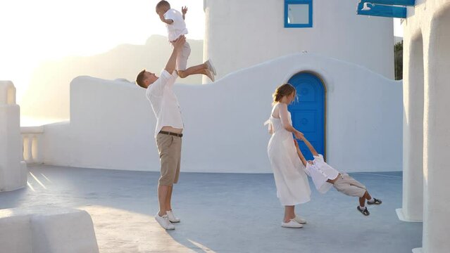 Happy family with children on vacation in Santorini, Greece. Parents have fun with their children.