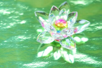 Crystal lotus on shiny green background with light reflection. Anahata chakra symbol