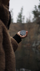 a man holds a compass near a river in the mountains