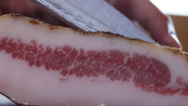 Cutting slice of guanciale italian salumi for spaghetti alla carbonara amatriciana