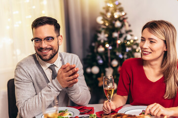Couple drinking wine and laughing while sitting around a dining table during a dinner party