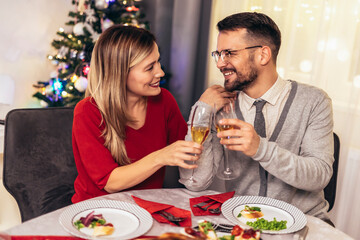 Couple drinking wine and laughing while sitting around a dining table during a dinner party