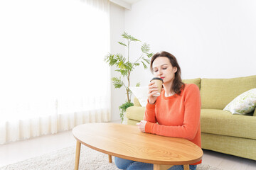 家でコーヒーを飲む若い女性