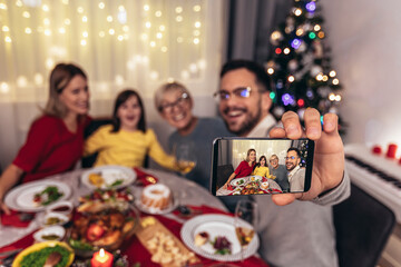 Obraz na płótnie Canvas Happy multi-generation family enjoying in a lunch together at home. Family on Christmas dinner at home make selfie photo.