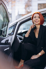 Business woman sitting in electric car at the electric charging station