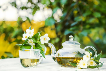 Philadelphus or garden jasmine flowers, healthy herbal tea cup of hot tea. Romantic dinner with therapeutic fragrant tea.