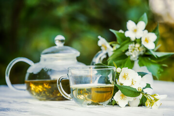 Philadelphus or garden jasmine flowers, healthy herbal tea cup of hot tea. Romantic dinner with therapeutic fragrant tea.