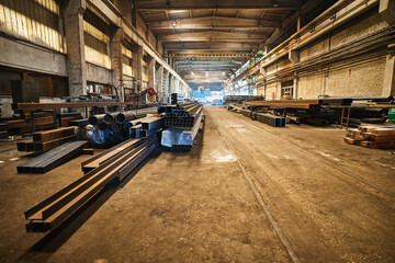 Wide angle shot of old long metalworking factory crammed with metal and spare parts