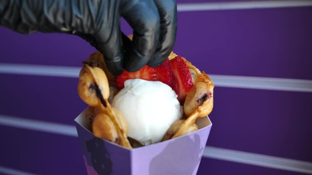 Chef decorates Hong Kong bubble waffle with ice cream berries.