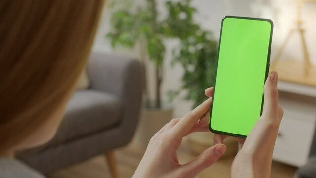 Back View of Woman at Phone with Green Screen for Copy Space. Chromakey Mock Up Without Tracking Markers. Close Up. Girl is Surfing Content With Touching Tapping on Center Screen