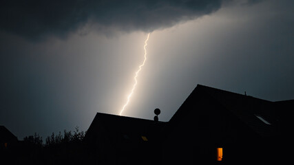 Naklejka na ściany i meble lightning in the sky over houses in the city at night