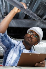 man inspecting metal cross beam in roof space