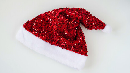 Close-up of a red shiny santa claus hat on a white background,top view, flat lay, copy space. Decor concept for christmas or new year party. Christmas suit.