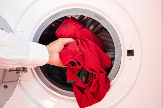 Closeup of a hand of a man putting dirty cloth into the washing machine