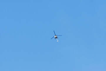 Fototapeta na wymiar Helicopter flying high in the sky, Netherlands. With a clear blue skyaltitude