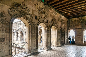 Nice view inside a room with a wooden floor, wooden beam ceiling and Baroque reliefs carved out of the sandstone wall of the famous Porta Nigra, a large Roman city gate in Trier, Germany.  - obrazy, fototapety, plakaty