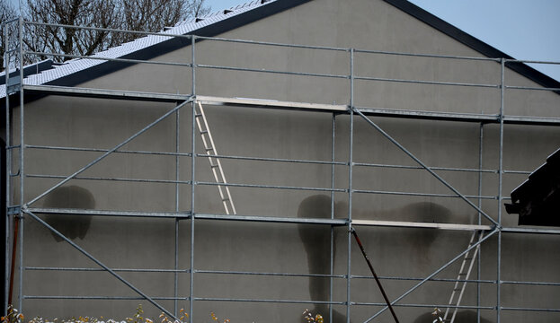 mobile scaffolding on the house where the facade of a collapsible and quickly erected portable multi-story family, apartment house is being completed. tools, equipment rental. worker avoids climbing