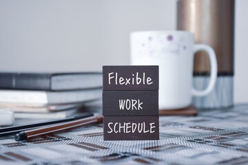 Wooden chips with the inscription Flexible Work Schedule on workplace background. 