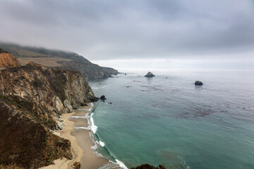 The Big Sur coastal area with crags and cliffs in the US state of California on a cloudy foggy day,...