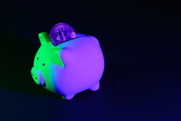 Piggy bank on a dark background with Bitcoin and green-purple backlight. Banking concept. Bitcoin mining concept
