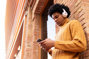 Black young man listening to music with headphones and smartphone