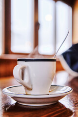 Hot Espresso coffee cup with coffee set spoon and plate on wood table with window at background on mountain bar