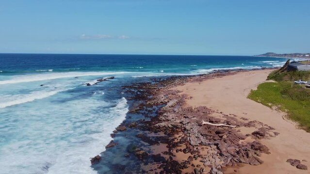 Mesmerizing blue sea splashing waves on the sandy shoreline in Scottburgh, Sout Africa