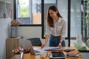 Asian businesswoman standing and holding documents while working in an office