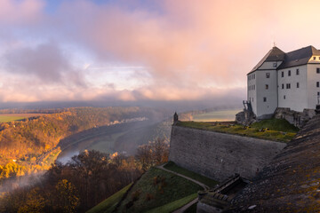 Festung Königstein im Morgenlicht mit Nebel über dem Fluss Elbe in der Sächsischen Schweiz im...