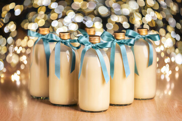 Homemade eggnog in bottles with blue bows on light spotty background