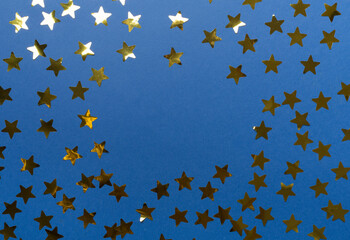 Golden confetti stars on color background, top view