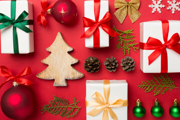 Flat lay with christmas gift boxes, toys, juniper and cones on color background