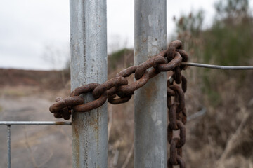 Old rusted iron chain on a metal gate of a property