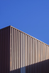 Brown Corrugated Steel Wall of Warehouse Building with sunlight on surface with blue clear sky background in Vertical frame