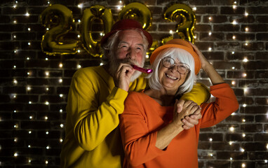Fototapeta na wymiar Celebrate event new year for couple of nice people - beautiful senior adult man and woman having party by night. Happiness lifestyle for mature retired people, party lights