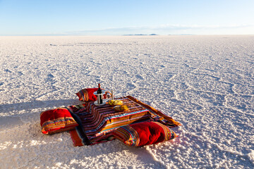 Colourful low table and cushions set for a sunset cocktail in the Uyuni Salt Flats seen during a sunny spring golden hour, Bolivia - obrazy, fototapety, plakaty