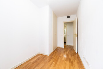 Empty bedroom with white wooden built-in wardrobe doors and ducted air conditioning, white painted walls and wooden floors